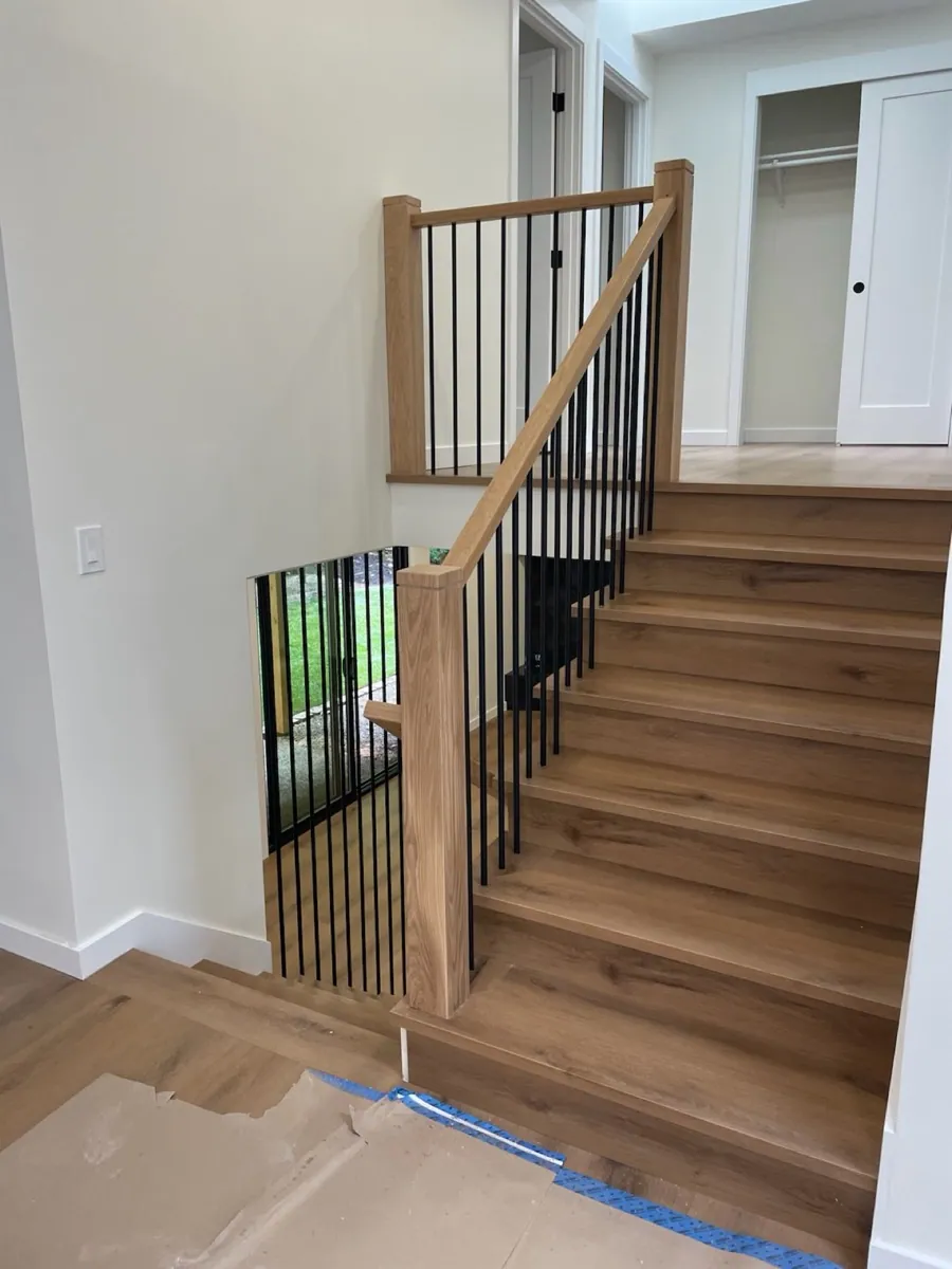 Custom light oak staircase with modern black metal railing in a Seattle home