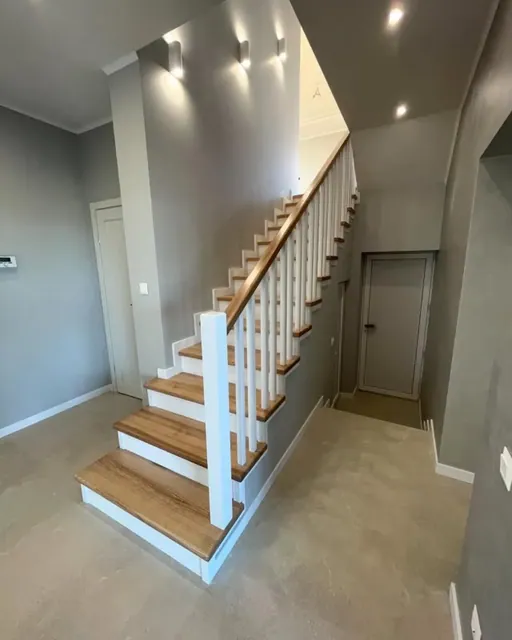 Wood stair railing with oak handrail and white balusters in a Seattle home